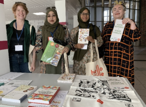 Wen Food Lives Team holding up books infront of a table with a display of books.