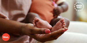 Hand of woman with painted finger nails holding a babies feet.